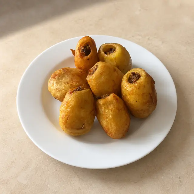 Siete papas rellenas doradas servidas en un plato blanco